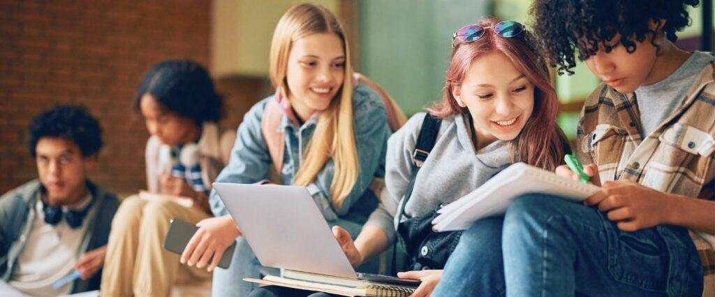 A diverse group of students collaborating in a study session, using laptops and notebooks in a modern learning environment.